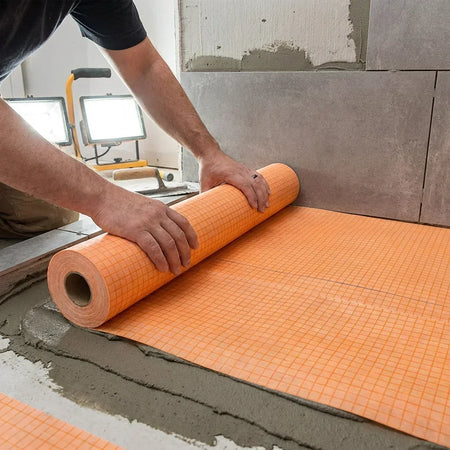 Waterproof Tile Membrane 1m x 30m Roll CUPc ICC-ES Certified Shower Bathroom Kitchen Waterproofing | British Building Supplies | Person unrolling an orange tile underlayment on a floor
